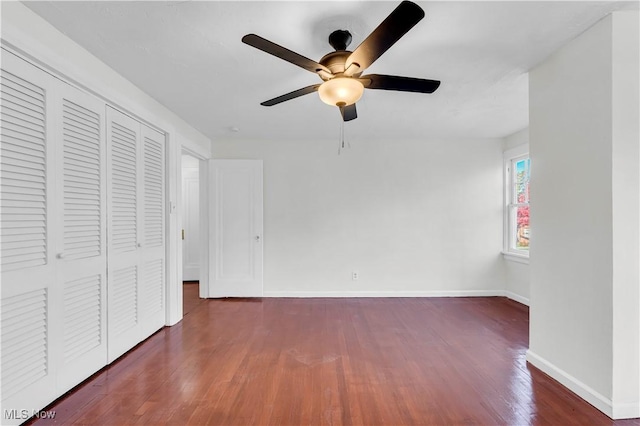 unfurnished bedroom with a closet, dark wood finished floors, a ceiling fan, and baseboards