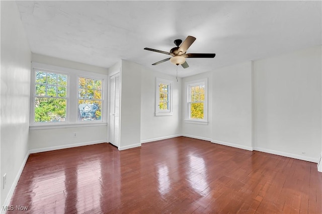 unfurnished room with a ceiling fan, dark wood finished floors, and baseboards