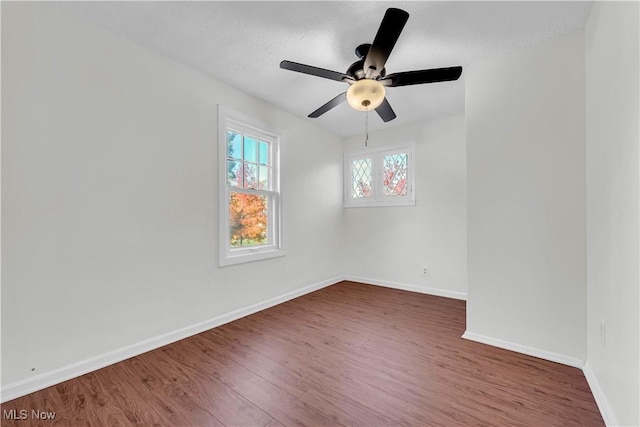 unfurnished room featuring dark wood finished floors, baseboards, and ceiling fan