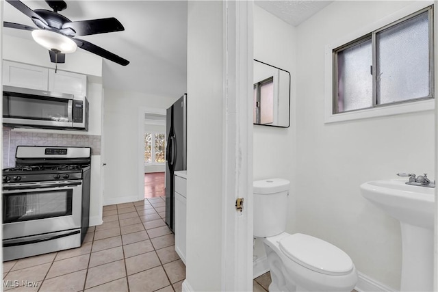 bathroom featuring tasteful backsplash, toilet, a ceiling fan, baseboards, and tile patterned floors