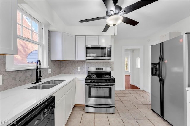 kitchen with stainless steel appliances, decorative backsplash, white cabinetry, a sink, and light tile patterned flooring