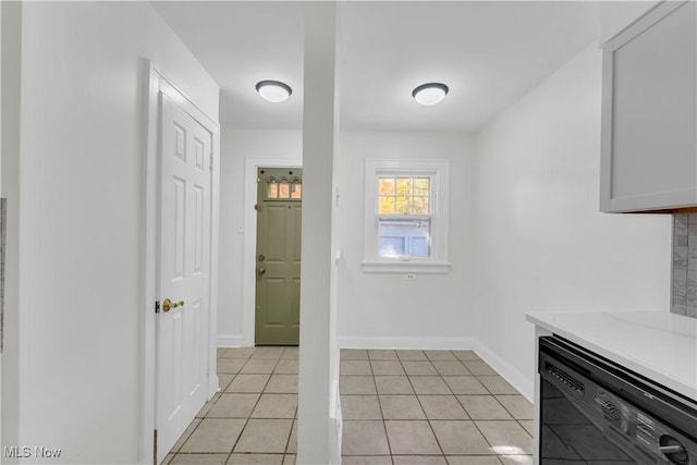 interior space with light tile patterned floors, light countertops, white cabinetry, dishwasher, and baseboards