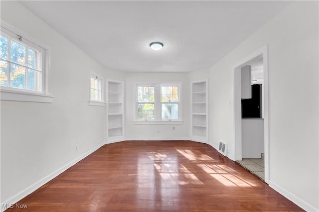 interior space featuring baseboards, visible vents, built in features, and wood finished floors