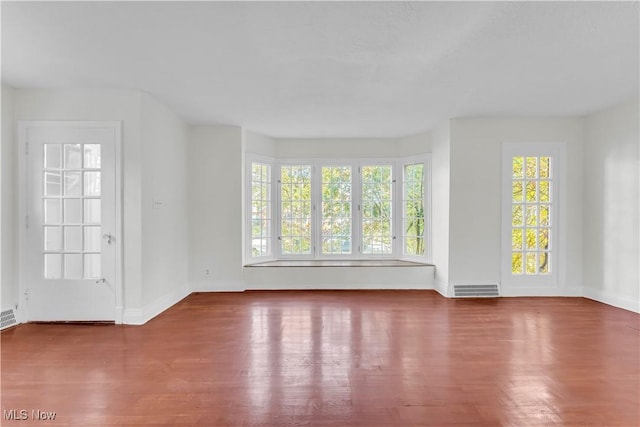 unfurnished living room with baseboards, visible vents, and wood finished floors