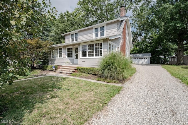 view of front facade with a garage, an outbuilding, a chimney, and a front lawn