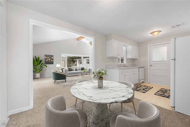 dining space with light colored carpet, visible vents, a ceiling fan, vaulted ceiling, and baseboards