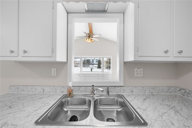 kitchen featuring lofted ceiling, light countertops, a sink, and white cabinets