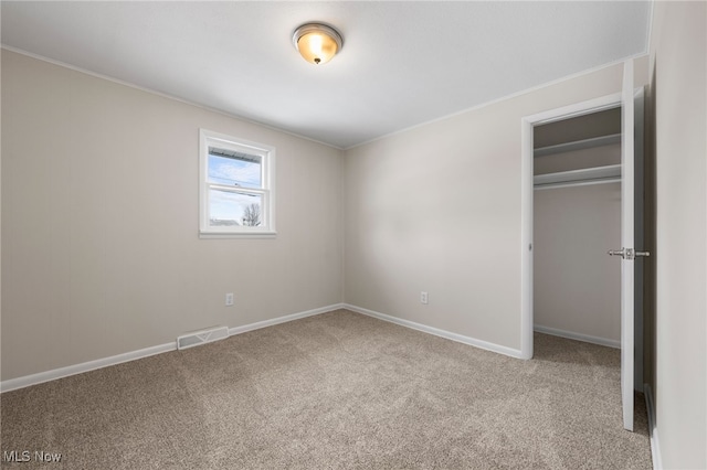 unfurnished bedroom with carpet floors, visible vents, baseboards, ornamental molding, and a closet