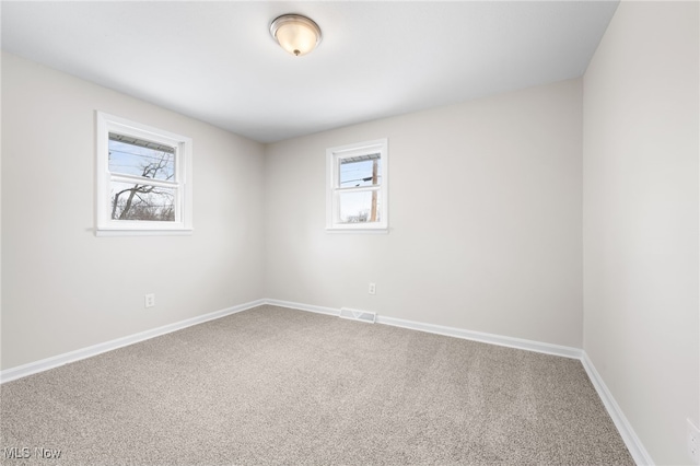 carpeted spare room with visible vents and baseboards