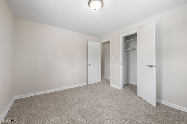 unfurnished bedroom featuring light carpet, baseboards, and a closet