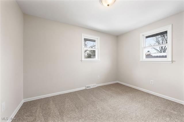 carpeted empty room featuring baseboards and visible vents