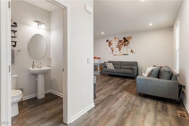 half bathroom featuring baseboards, visible vents, toilet, and wood finished floors