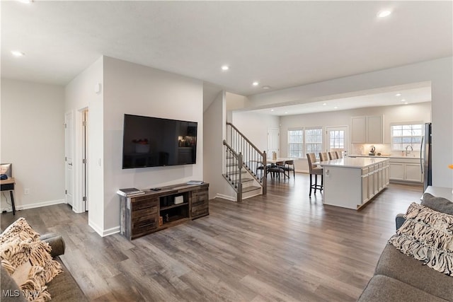 living area with baseboards, stairway, wood finished floors, and recessed lighting