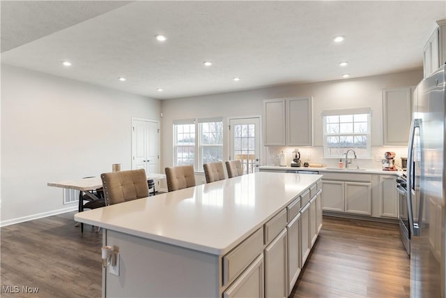 kitchen featuring stainless steel appliances, light countertops, a kitchen island, and a sink