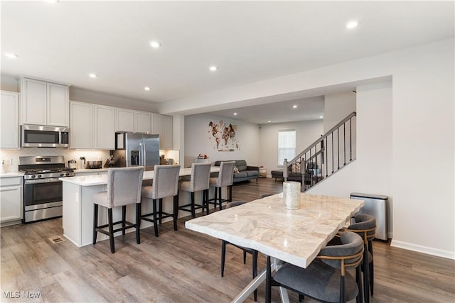 kitchen featuring a center island, white cabinetry, a kitchen breakfast bar, appliances with stainless steel finishes, and decorative backsplash