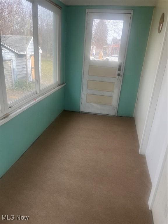 doorway to outside featuring plenty of natural light and light colored carpet