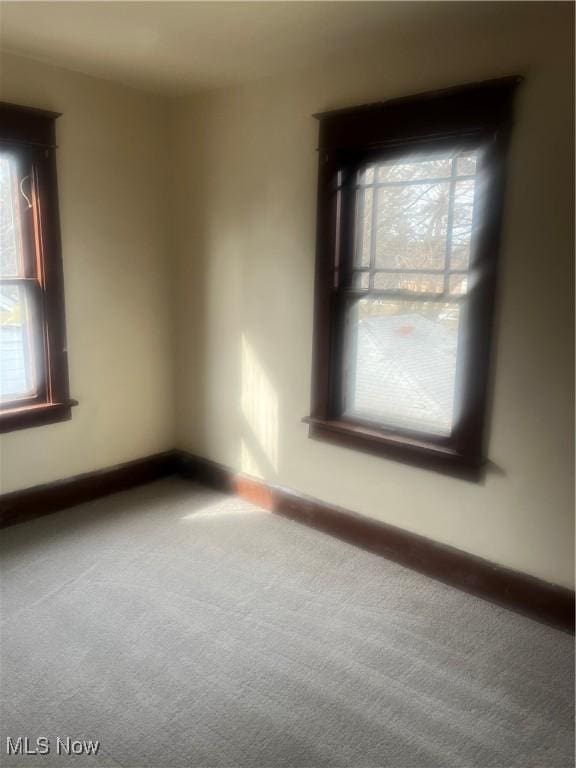 carpeted spare room featuring baseboards