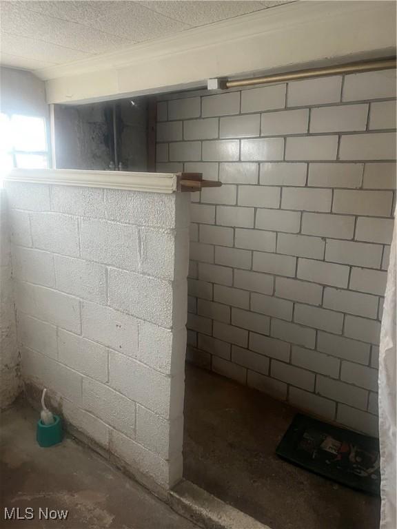 full bathroom with a textured ceiling, walk in shower, concrete block wall, and unfinished concrete floors