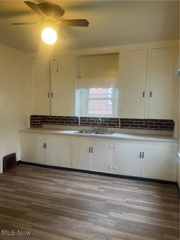 kitchen with visible vents, white cabinetry, decorative backsplash, and a sink