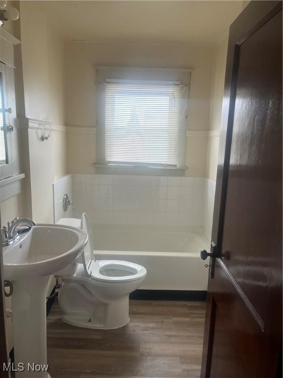 bathroom featuring toilet, a bathing tub, and wood finished floors