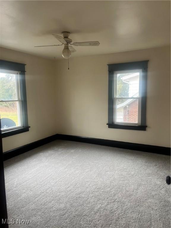 carpeted spare room featuring ceiling fan and baseboards