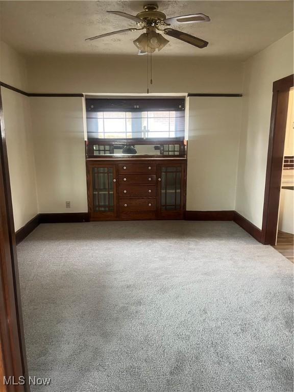 unfurnished living room with light carpet, ceiling fan, and baseboards