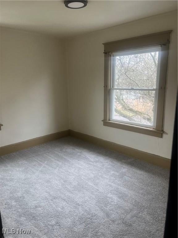 carpeted spare room featuring baseboards