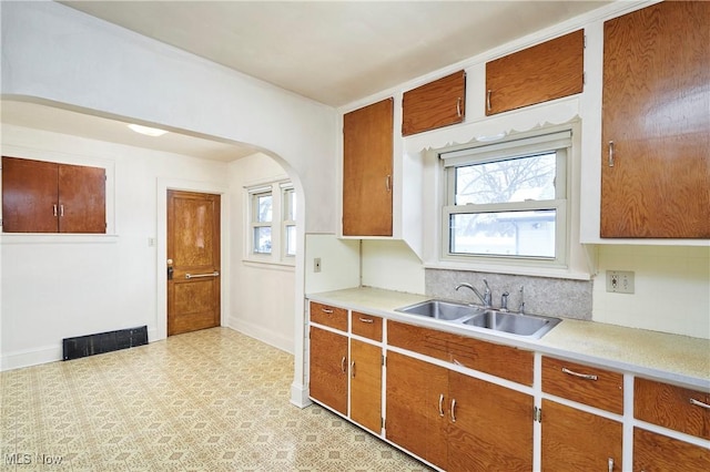 kitchen with arched walkways, light floors, light countertops, visible vents, and a sink