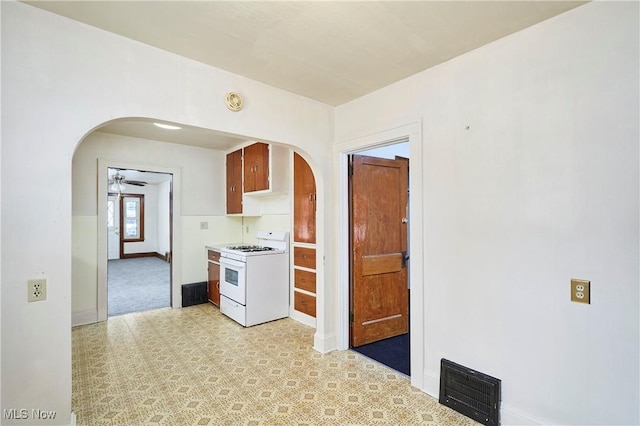 kitchen with visible vents, arched walkways, baseboards, white gas range, and light countertops