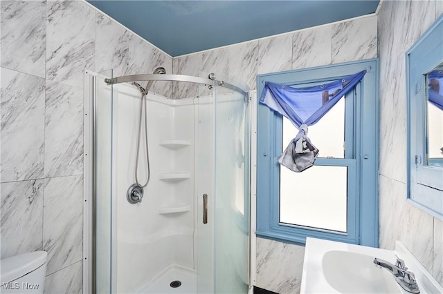 full bathroom featuring a stall shower, a sink, toilet, and tile walls