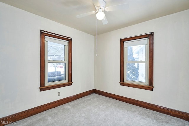 unfurnished room with baseboards, a ceiling fan, and light colored carpet