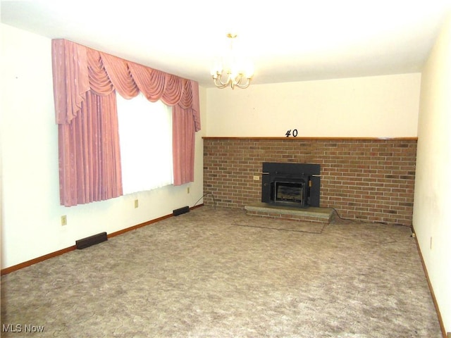 unfurnished living room featuring carpet floors, a notable chandelier, a fireplace, and baseboards