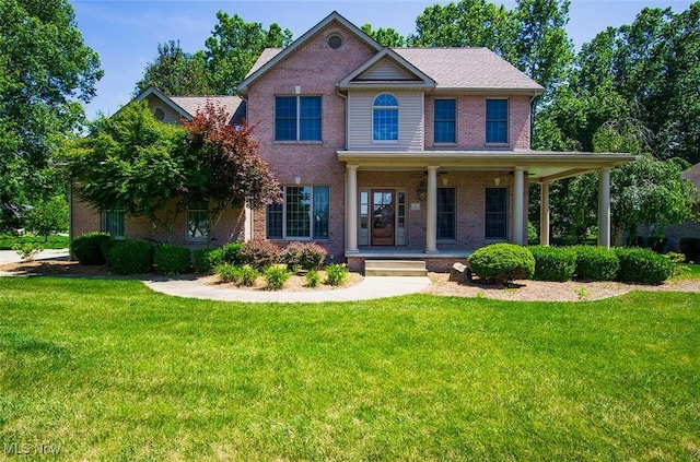 view of front facade with covered porch, a front lawn, and brick siding