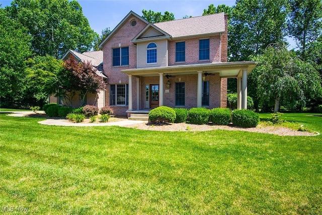 view of front of property featuring brick siding, ceiling fan, and a front yard