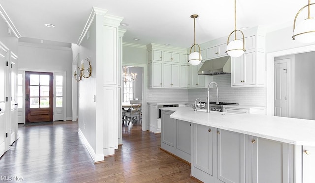 kitchen featuring hanging light fixtures, decorative backsplash, a center island with sink, and under cabinet range hood