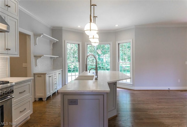 kitchen featuring a sink, light countertops, open shelves, an island with sink, and pendant lighting