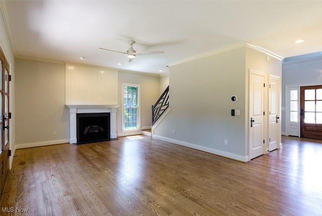 unfurnished living room featuring a fireplace with flush hearth, a wealth of natural light, baseboards, and wood finished floors