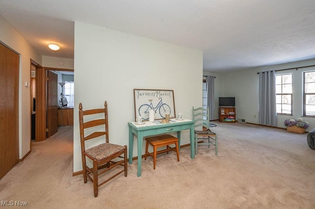 living area featuring baseboards, visible vents, and light colored carpet