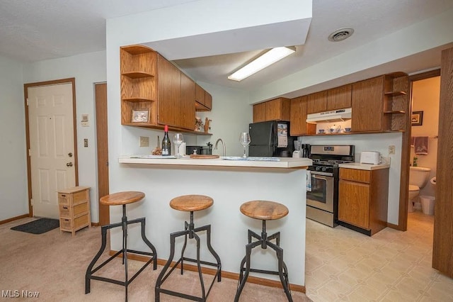 kitchen featuring open shelves, gas stove, light countertops, and under cabinet range hood