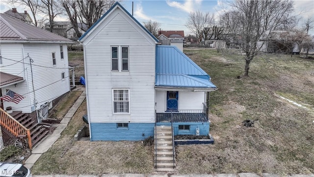 view of front of property with stairs, metal roof, and a porch