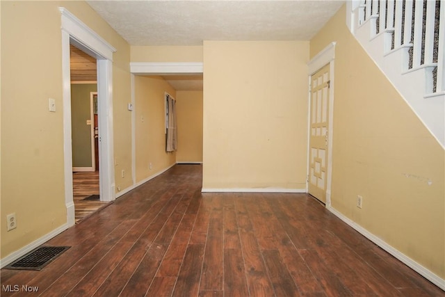 interior space with stairway, dark wood-style flooring, visible vents, and baseboards