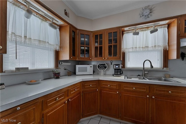 kitchen with white microwave, light countertops, a sink, and brown cabinetry