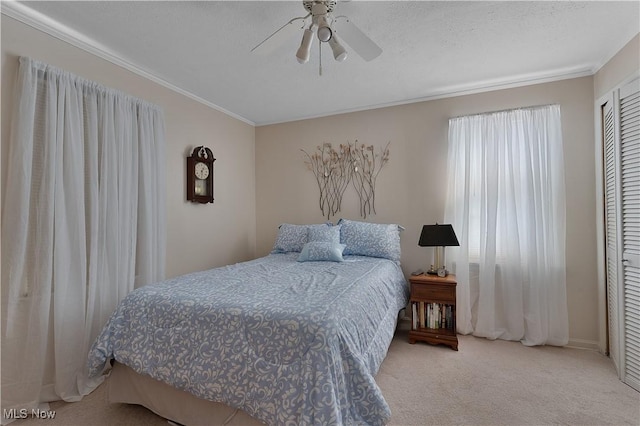 bedroom with a ceiling fan, a textured ceiling, ornamental molding, and carpet flooring