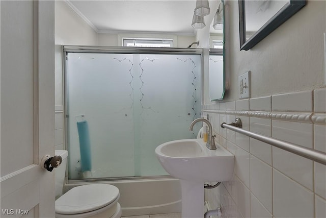 full bath featuring toilet, ornamental molding, combined bath / shower with glass door, and tile walls