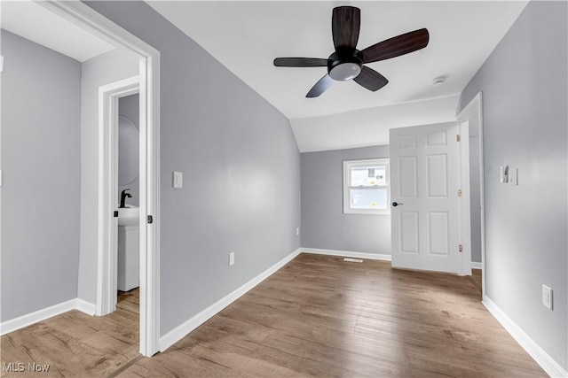 interior space with light wood-type flooring, ceiling fan, baseboards, and lofted ceiling