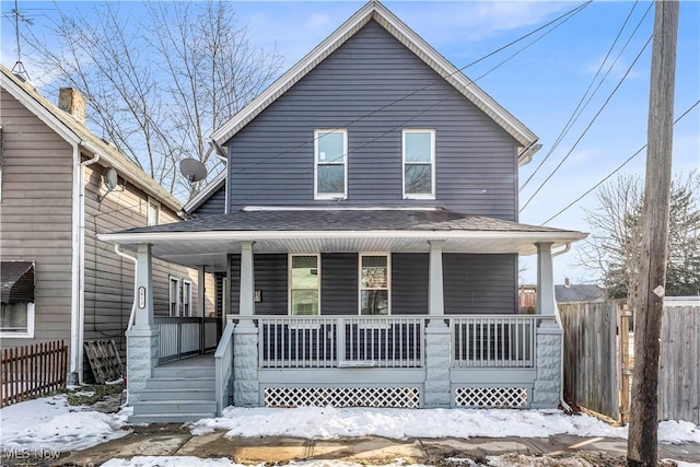 view of front of property with a porch, roof with shingles, and fence