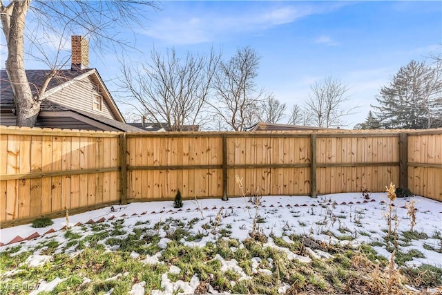 yard covered in snow with a fenced backyard