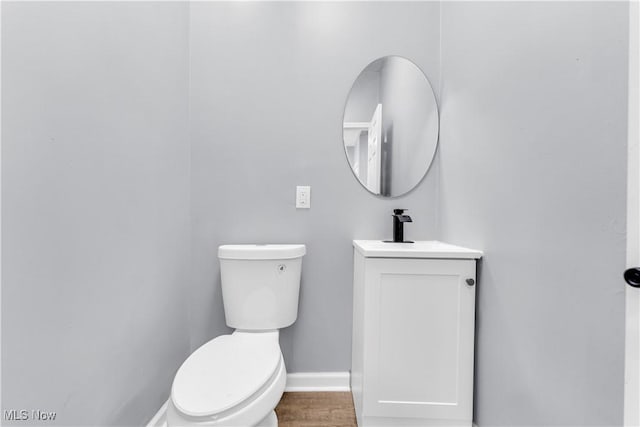 bathroom featuring baseboards, vanity, toilet, and wood finished floors