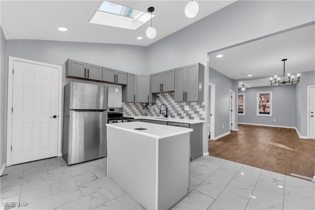 kitchen featuring marble finish floor, a kitchen island, appliances with stainless steel finishes, and light countertops