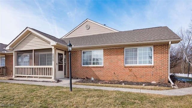 bungalow-style home with brick siding, a front yard, and a shingled roof